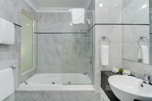 布里斯班麦克阿瑟钱伯斯酒店的白色的浴室设有浴缸和水槽。