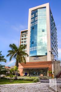 累西腓Marante Executive Hotel的一座高大的建筑,前面有一棵棕榈树
