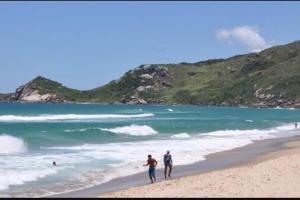 弗洛里亚诺波利斯APTO fino área nobre dos Ingleses. 500m da praia!的两人在海边的海滩上散步