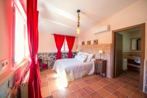 Los NavalucillosCasa Rural Encinar de las Flores的卧室配有红色窗帘的床