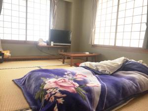 Saitobusiness ryokan haniwa的一张带蓝色毯子的床铺,地板上设有窗户