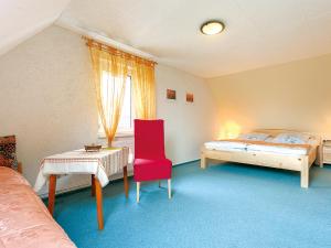 巴贝Ferienhaus in Baabe D 092.049的一间卧室配有一张床、一张桌子和一把红色椅子