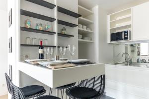 巴黎帕莱斯艾拓公寓式酒店的厨房设有酒吧,配有椅子和酒杯