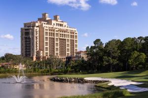 奥兰多奥兰多华特迪士尼世界度假区四季酒店的一座大建筑,位于一座建筑前面的池塘旁