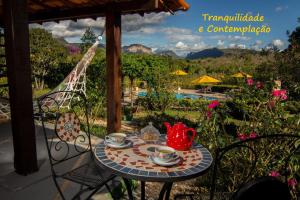 韦尔卡鲍Pousada Villa Lagoa das Cores的露台上的桌子上放着杯子和茶壶