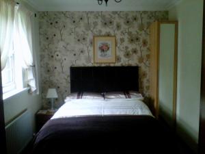 葛特纳格林查理王子小屋酒店的一间卧室配有一张华丽壁纸床