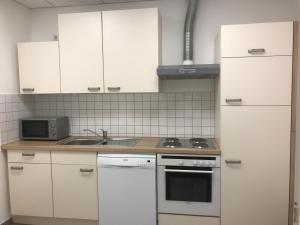 路德斯塔德·威特比Am Bahnhof的厨房配有白色橱柜和炉灶烤箱。
