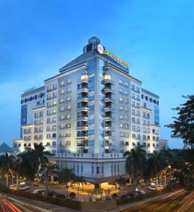 棉兰Grand Mercure Medan Angkasa的一座白色的大建筑,前面有棕榈树