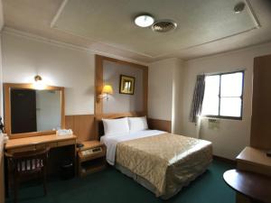 虎尾镇什叶派伊赫酒店的酒店客房带一张床、一张书桌和一面镜子