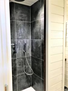 东方湾法国大街Studio La Voile Blanche的浴室设有黑色瓷砖淋浴。