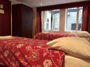 伦敦四星级酒店的卧室配有红色和白色的床,设有窗户