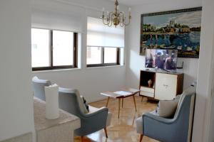 埃斯平霍Family Espinho Porto Guesthouse的客厅配有椅子、桌子和电视