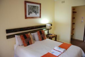 肯普顿帕克Journey's Inn Africa Airport Lodge的一间卧室配有带白色床单和橙色枕头的床。