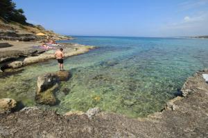 莱乌卡Le Dimore Sul Mare di San Gregorio的站在海滩水面上的男人