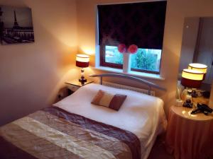 金塞尔Summer Cottage in Kinsale的一间卧室配有一张床,窗户配有两盏灯。