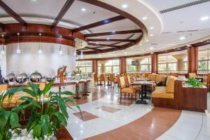 沙迦沙迦普瑞米尔度假酒店的餐厅设有配有桌椅的大型大堂。