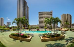 檀香山夏威夷阳光假日公寓的一座带游泳池、棕榈树和建筑的度假村