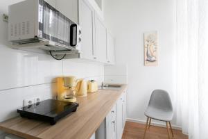 柏林City Studio Apartment in Friedrichshain的厨房配有白色橱柜和木制台面