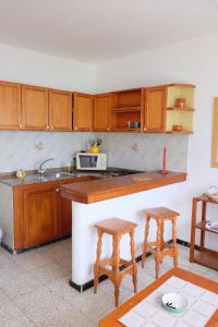 阿列塔SEA & RELAX - Apartament 2 Izq的厨房配有木制橱柜、水槽和2张凳子