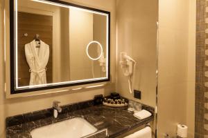 安卡拉Hm商务酒店的浴室配有盥洗盆、镜子和浴袍
