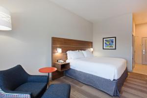 科罗娜Holiday Inn Express & Suites Corona, an IHG Hotel的配有一张床和一把椅子的酒店客房