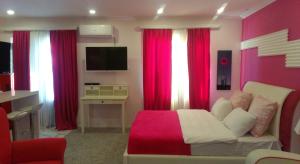 Nizhnyaya AlekseyevkaPink Apartment near Airport的一间卧室配有红色窗帘、一张沙发和一台电视