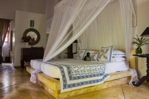 乌纳瓦图纳Why House的卧室配有带白色床单和枕头的天蓬床。