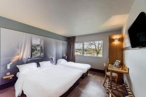 贝桑松B&B HOTEL Besançon Chateaufarine的卧室配有一张白色大床和电视。