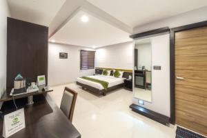 班加罗尔Treebo Trend Raj Premier - Indiranagar的配有一张床和一张书桌的酒店客房