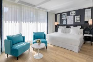 马德里易美吉因巴塞罗酒店&度假村的一间卧室配有一张大床和一张蓝色椅子