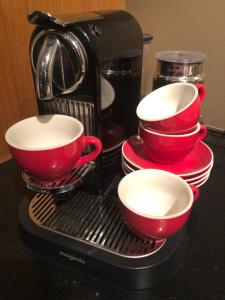 法尔肯堡Hotel Le Baroudeur的咖啡壶,带四个红杯和盘子
