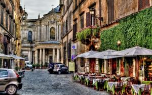 罗马罗马蒂布蒂娜套房酒店的城市里一条带桌子和遮阳伞的街道
