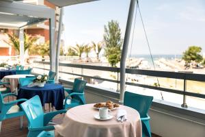 卡托利卡华尔多夫皇宫酒店的一间带桌椅的餐厅,享有海滩美景