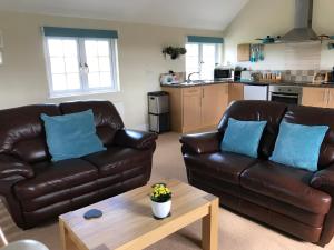 Broad ClystCrannaford Cottage的客厅配有两张真皮沙发和一张茶几