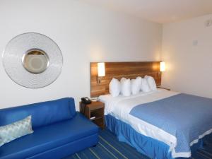 科尔尼Days Inn & Suites by Wyndham Kearney NE的酒店客房,配有床和蓝色的沙发