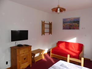 勒布罗伊斯Les Lys Orangés的客厅配有红色沙发和平面电视