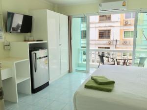 乔木提恩海滩泰国兰花经济型酒店的厨房配有带电视和冰箱的床铺。