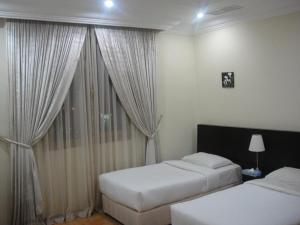 科威特海湾大陆公寓式酒店的一间卧室设有两张床,窗户配有窗帘