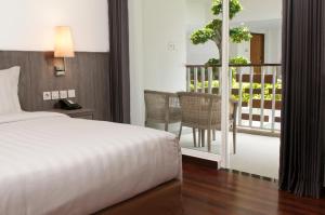 坎古ASTON Canggu Beach Resort的一间卧室配有一张床,阳台配有桌子