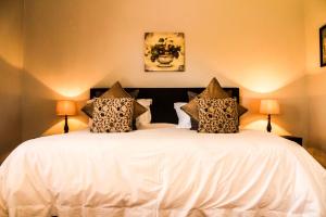 阿多杰拉德的礼物宾馆的一间卧室配有一张带两盏灯的大型白色床。