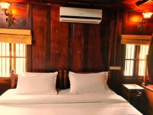 马拉利库兰Palathra Heritage的一张带白色床单和枕头的床