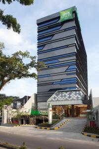 棉兰ibis Styles Medan Pattimura的一座高大的建筑,上面有标志