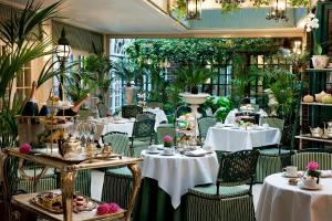 伦敦红色康乃馨切斯特菲尔德梅菲尔酒店的一间设有白色桌椅的餐厅,种植了植物