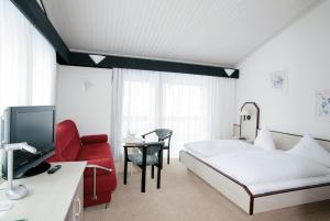 开姆尼茨阿本德罗特酒店的酒店客房,配有一张床和一张红色椅子