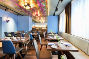 慕尼黑威斯特安德酒店（禁烟）的餐厅设有木桌和椅子,拥有色彩缤纷的天花板