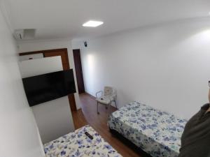 南圣克鲁斯Mini Kitnet - Santa Cruz do Sul的小房间设有两张床和一台平面电视