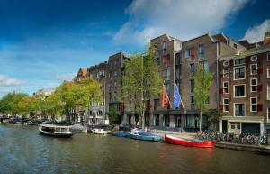 阿姆斯特丹阿姆斯特丹安达仕王子运河凯悦概念酒店的一群船在建筑物旁边的河流里