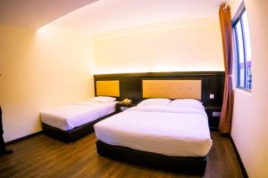 诗巫苏拉酒店的酒店客房设有两张床和窗户。