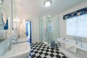 格拉夫-里内特Drostdy Hotel的浴室配有2个盥洗盆、浴缸和淋浴。
