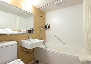金泽金泽站前永安国际酒店 的一间带水槽、浴缸和镜子的浴室